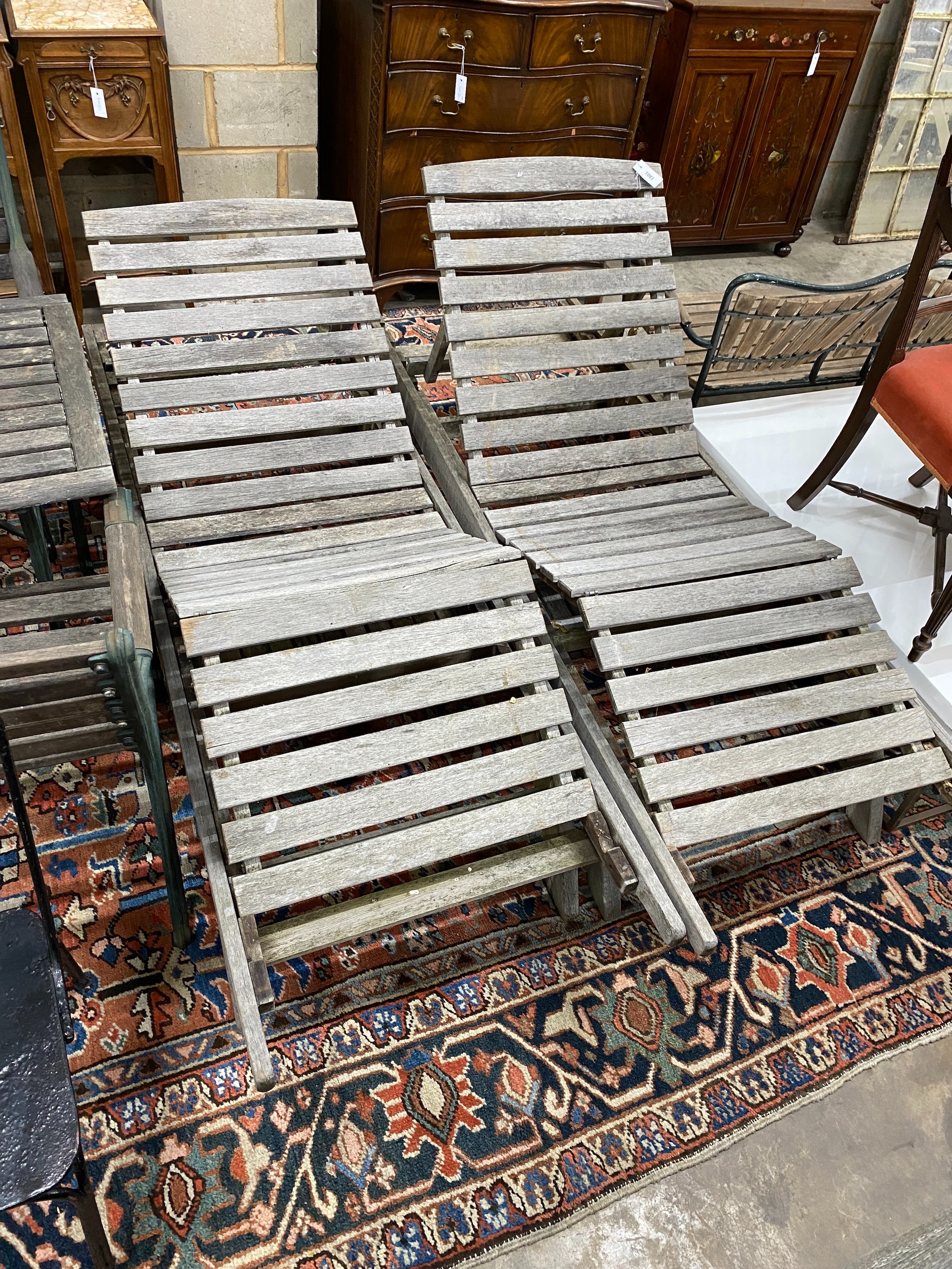 A pair of weathered teak garden loungers